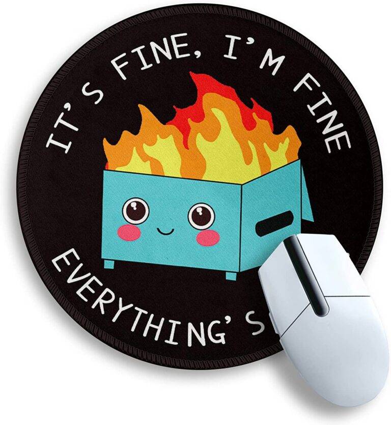 The image shows a cartoon dumpster on fire on a mouse pad. The dumpster is overflowing with trash and flames are shooting out of the top. The mouse pad is black with a stitched edge.