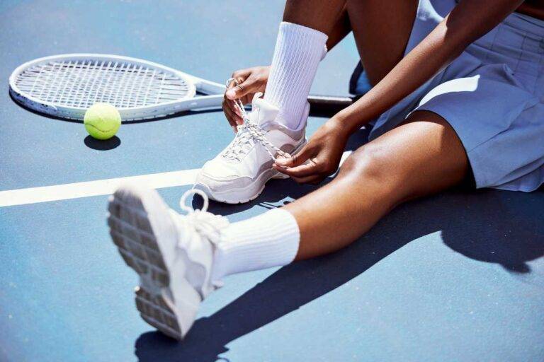 girl tying shoes in tennis court